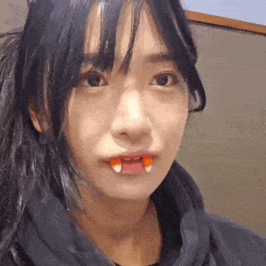 a close up of a woman with candy corn in her mouth .