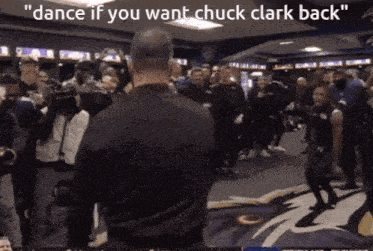 a man stands in front of a crowd with the words " dance if you want chuck clark back " on the bottom