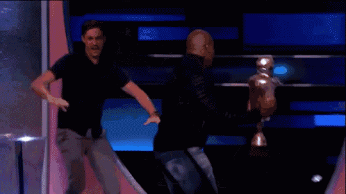 two men are dancing on a stage with a trophy in the background .