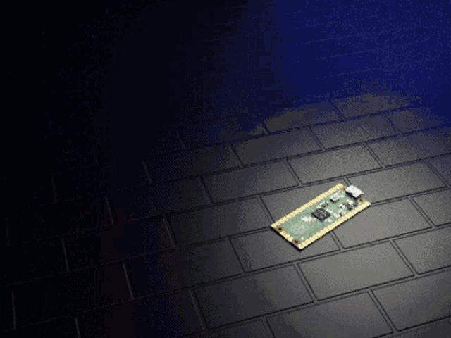a green and gold motherboard is laying on a black brick floor