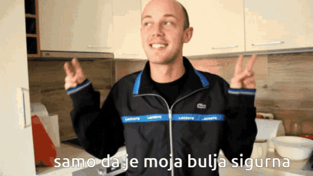 a man in a black lacoste jacket is giving a peace sign