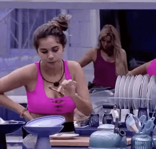 a woman in a pink sports bra is standing in front of a dish rack