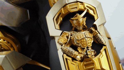 a close up of a gold armored figure with the letter d on it