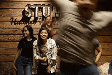 a group of people are posing for a picture in front of a wooden sign .