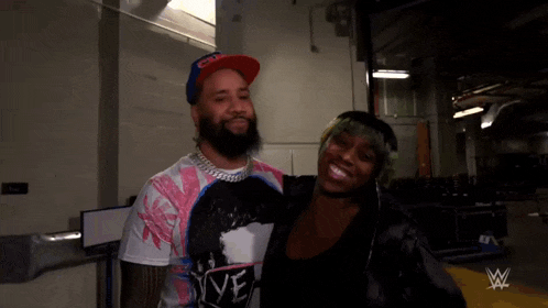 a man and a woman are posing for a picture in a room with a wwe logo in the background .