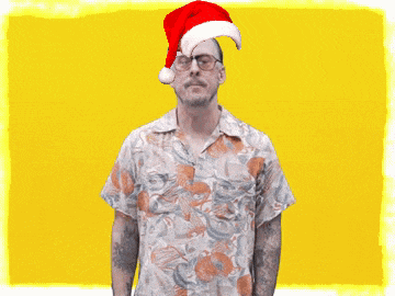 a man wearing a santa hat and a hawaiian shirt stands with his arms outstretched