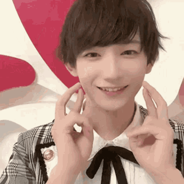 a young man is making a peace sign with his hands in front of a red heart .