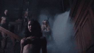 a woman in a gas mask is walking through a dark room .