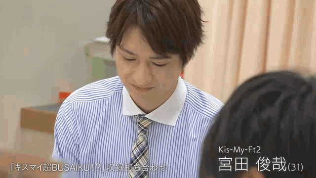 a man in a striped shirt and tie with kis-my-ft2 written above him
