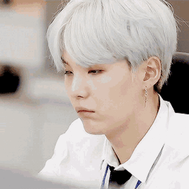 a man with white hair is wearing earrings and a tie
