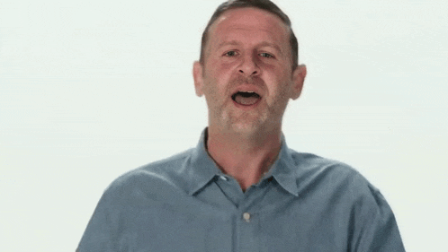 a man in a blue shirt is making a funny face while looking at the camera .