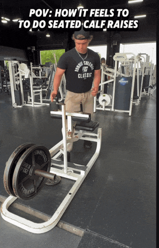 a man wearing a shirt that says marine college classic is doing seated calf raises in a gym