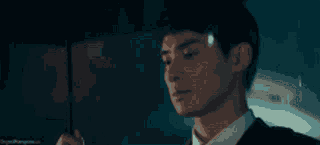 a man in a suit and tie is holding an umbrella in the dark .