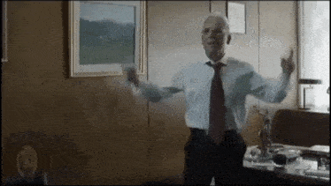 an older man in a suit and tie is dancing in a room .
