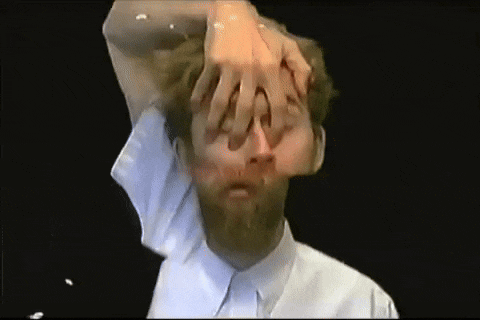a man with a beard has his hands on his head