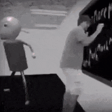 a man is writing on a blackboard while a robot is standing next to him .