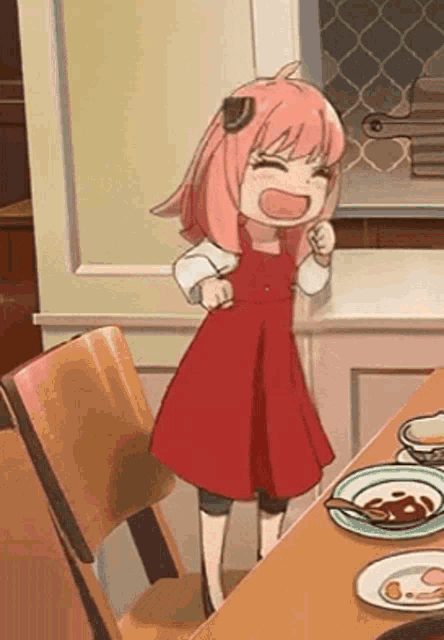 a little girl in a red dress is standing in front of a table .