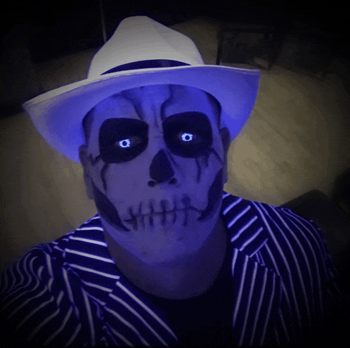 a man with a skeleton face paint and glowing eyes is wearing a white hat