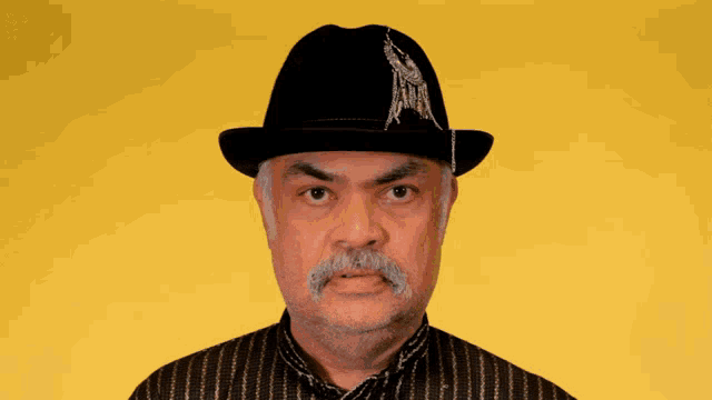 a man with a mustache wearing a black hat with the letter a on it