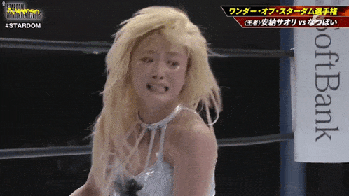 a woman is crying in a wrestling ring with a softbank sign in the background
