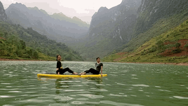 two women sit on a paddle board in a lake