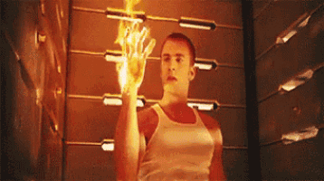 a man in a tank top is holding a fireball in his hand in a room .