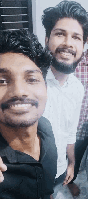 two men are posing for a picture together and one has a beard