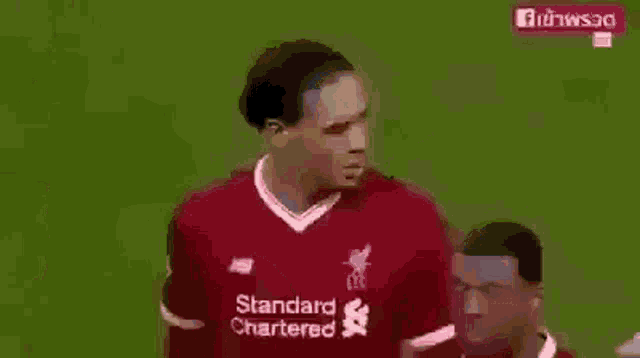 a soccer player wearing a red shirt that says standard chartered