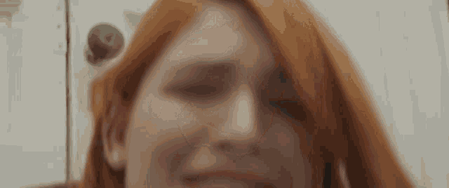a woman with red hair is looking at the camera