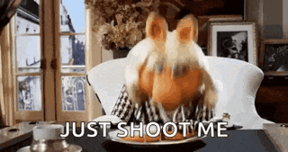 a stuffed animal is sitting at a table with a plate of food and the words just shoot me behind it .