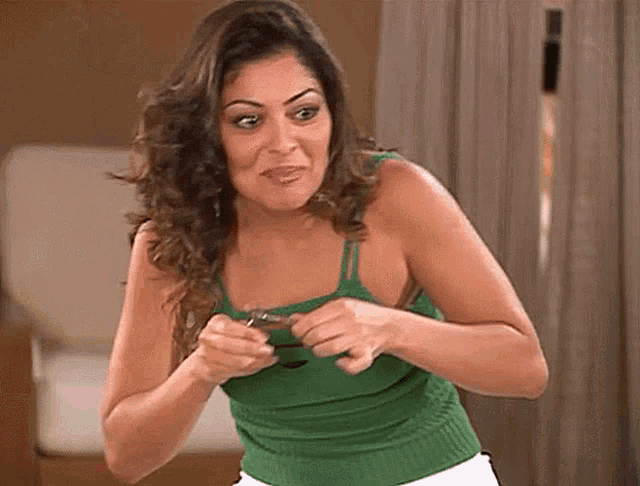 a woman in a green tank top is holding something