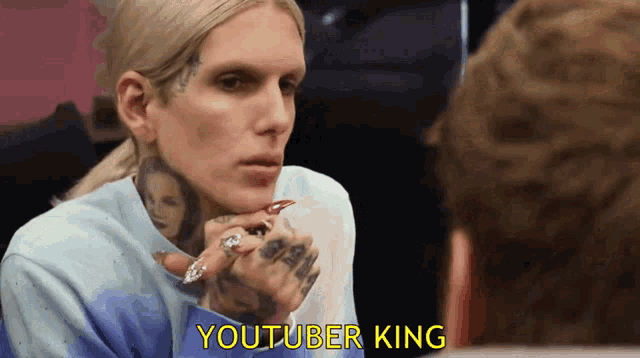 a man with a tattoo on his face is talking to another man with the words youtuber king above him
