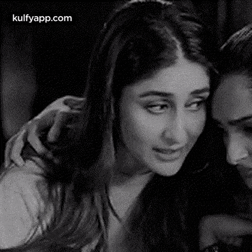 a black and white photo of a woman hugging another woman .
