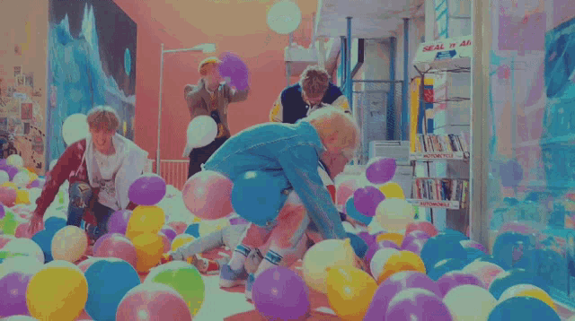 a group of people are playing with balloons in a room with a red wall
