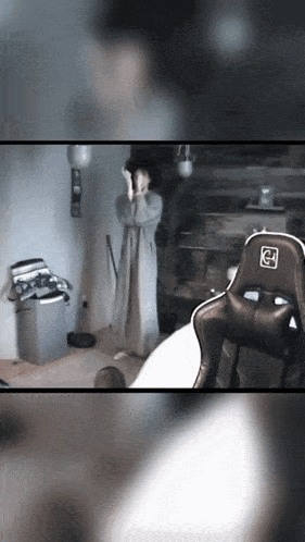 a blurred image of a person standing in front of a chair with the letter g on the back