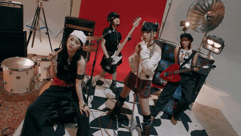 a group of girls playing instruments including a red guitar and a drum