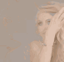 a woman with long blonde hair is holding her hand to her head .