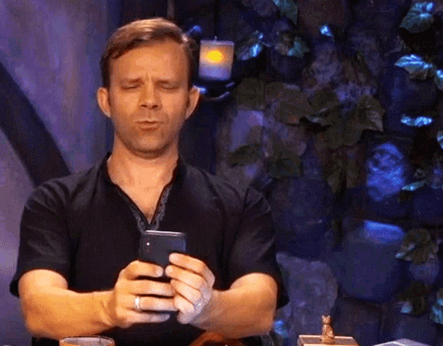 a man in a black shirt is looking at his cell phone