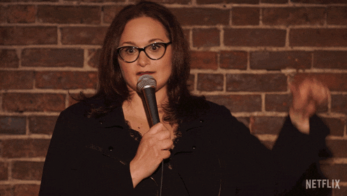 a woman giving a thumbs down in front of a brick wall with netflix written on the bottom right
