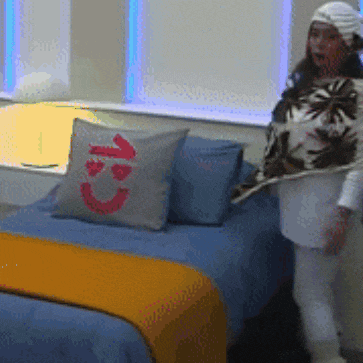a person standing next to a bed with a pillow with a smiley face and the number 13 on it