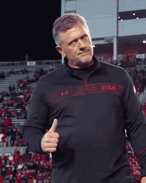 a man giving a thumbs up wearing a shirt that says utah on it