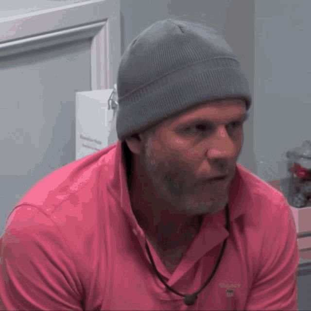 a man wearing a grey beanie and a pink shirt with the word gant on it