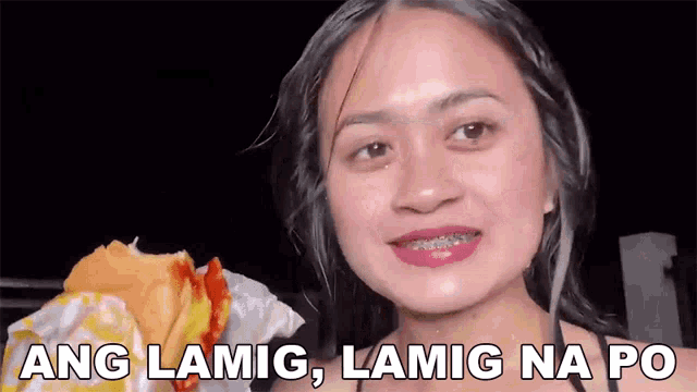 a woman with braces on her teeth is smiling while holding a hot dog and says ang lamig lamig na po