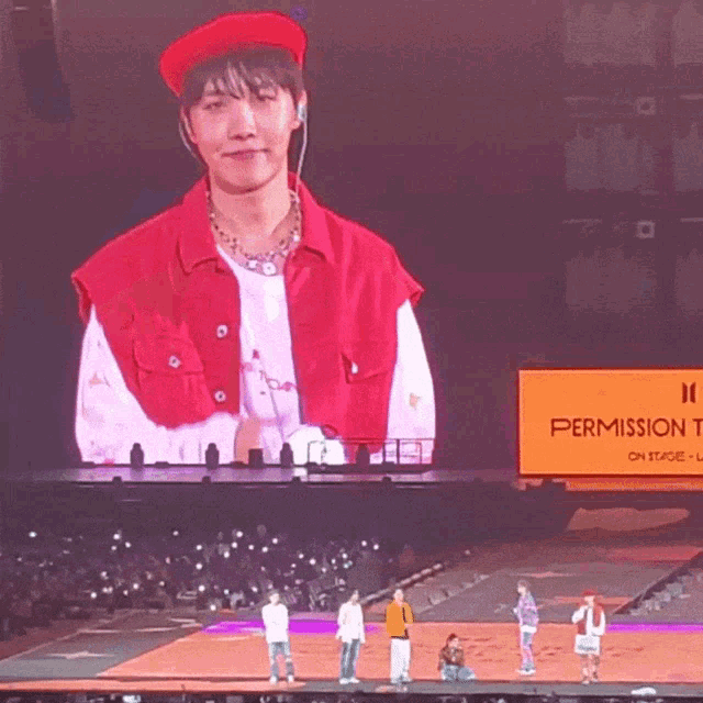 a man in a red hat is standing in front of a sign that says permission to dance