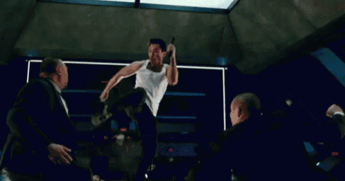 a man in a white tank top is jumping in the air in a room