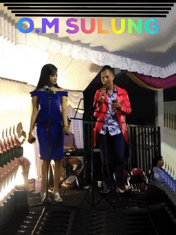 a man and a woman singing in front of a sign that says o.m sulung