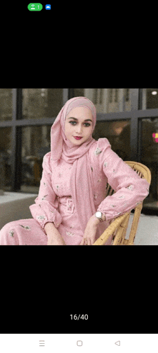 a woman in a pink dress and hijab is sitting on a chair