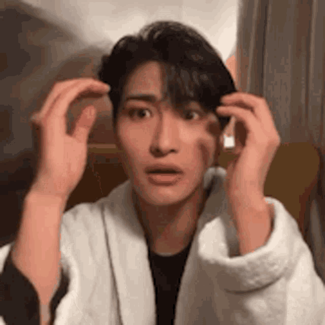 a young man in a white robe is making a funny face while sitting in a chair .