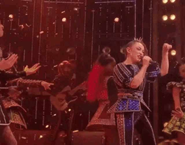 a woman singing into a microphone on stage