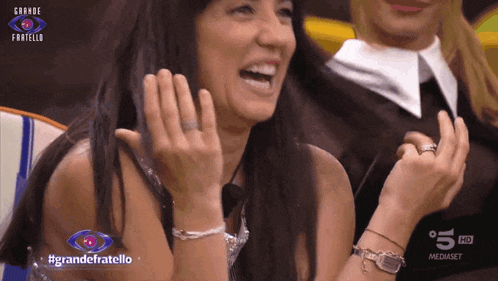 a woman is laughing in front of a sign that says grande fratello on it